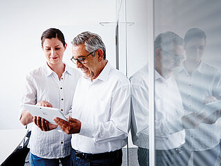 A man and a woman looking at a tablet