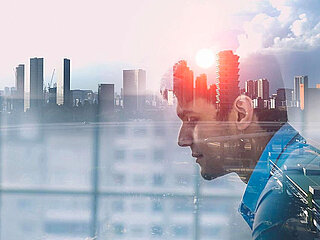 A man in profile and a skyline at sunset in the background