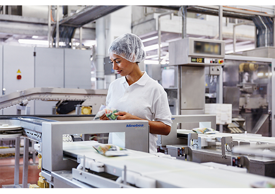 a woman in front of a inspection system in the dairy prodcution